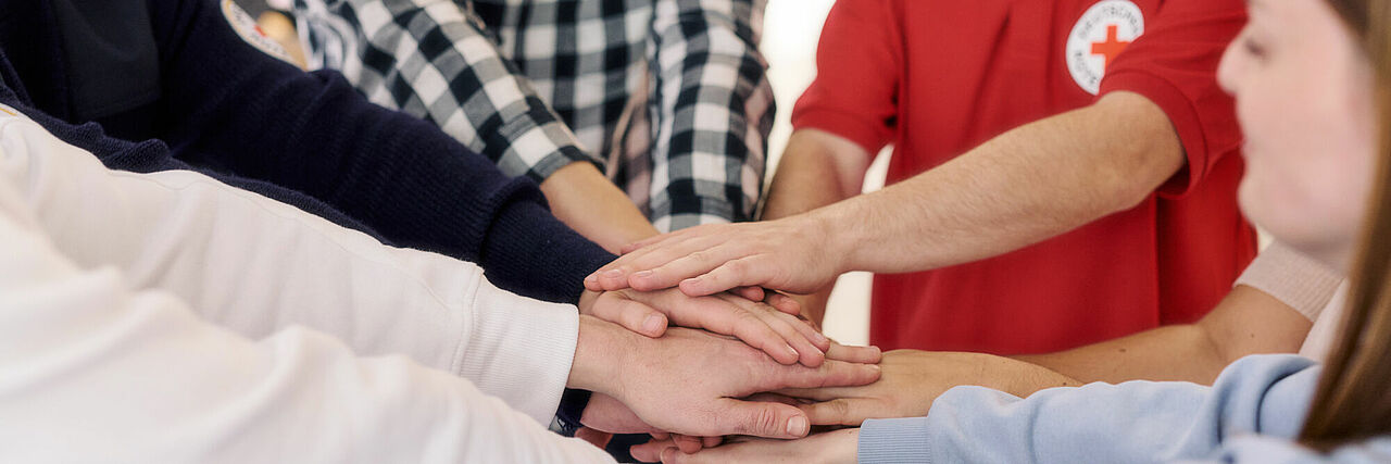 Mitarbeiter DRK schlagen die Hände gemeinschaftlich zusammen