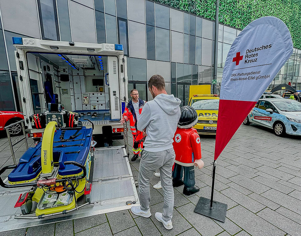 geöffnete Heckklappe eines Rettungswagens vor Flagge zur Blutspende